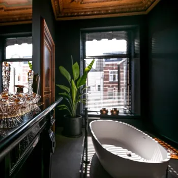 Stijlvolle B&B-kamer met vrijstaand bad, donkere muren en hoge ramen met uitzicht over de stad.